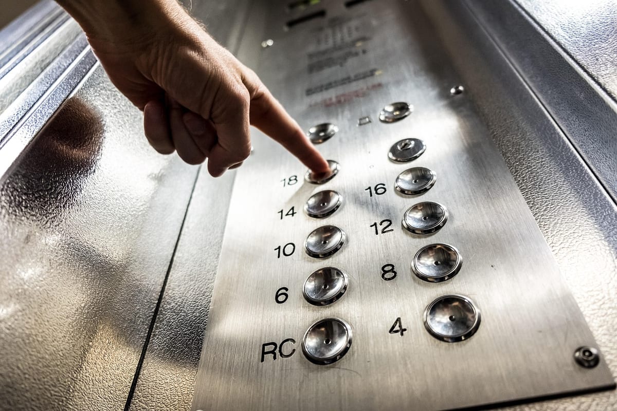 Un doigt appuie sur le bouton d'un ascenseur