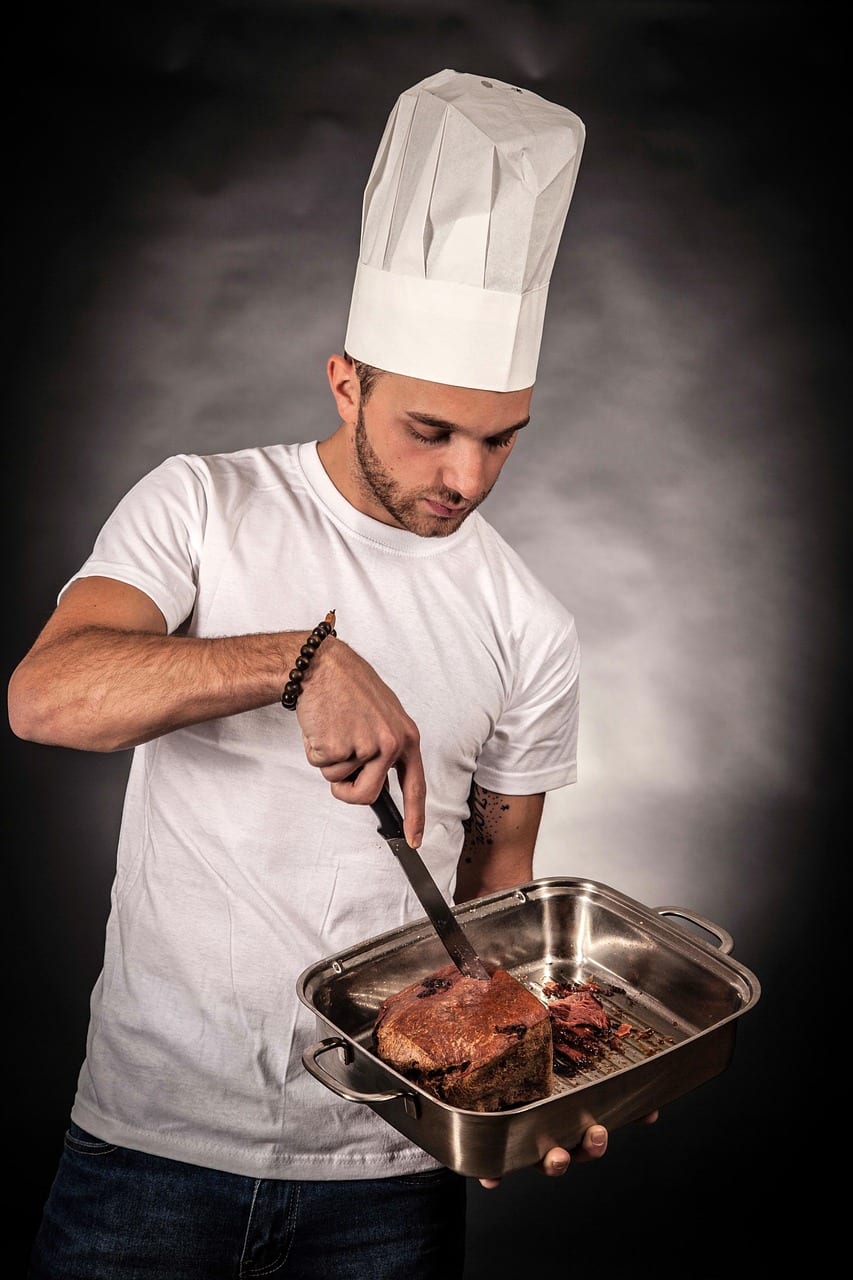 Un chef de cuisine en toque prépare un plat dans sa cuisine