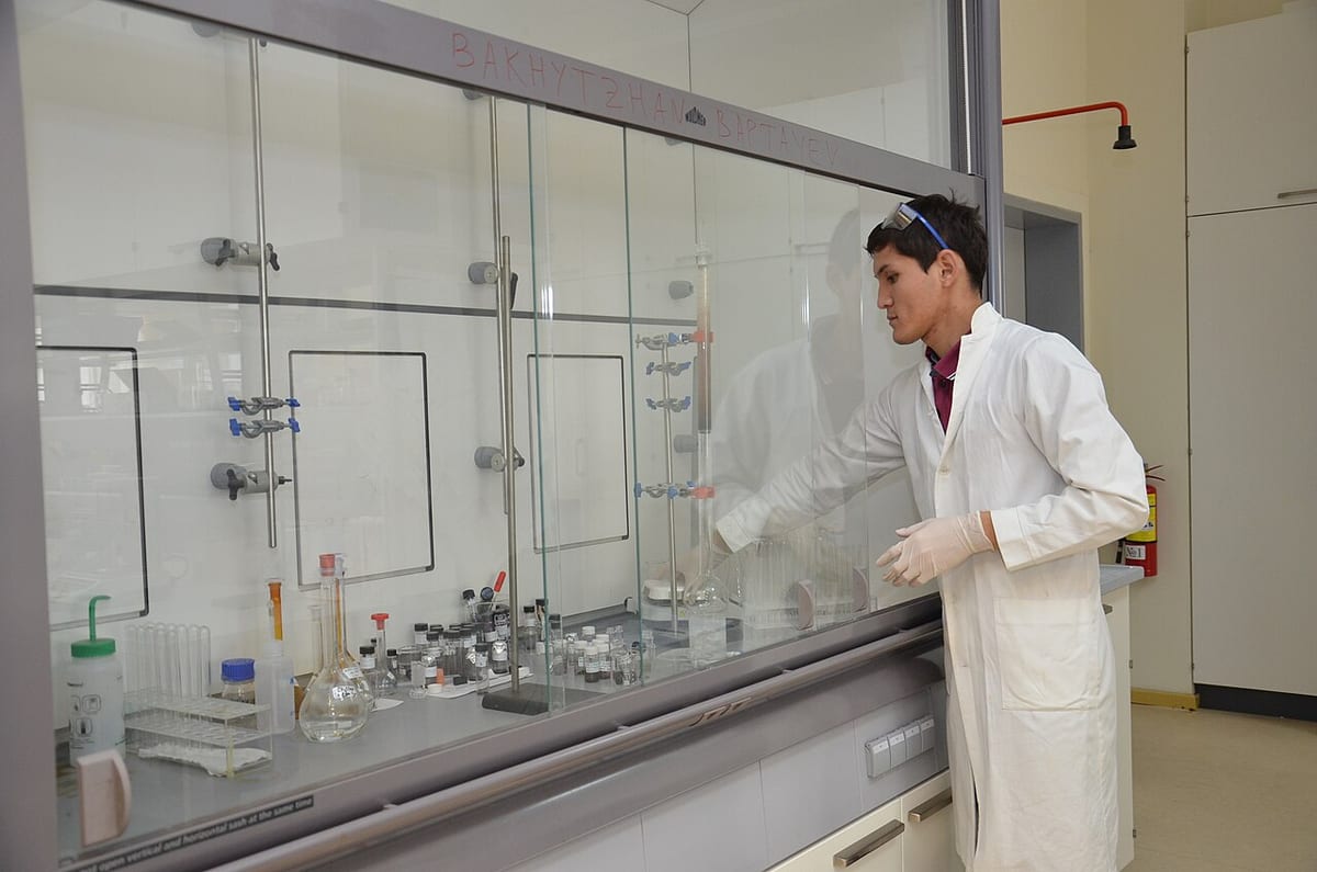 Un chercheur en blouse blanche travaille sous une sorbonne de laboratoire