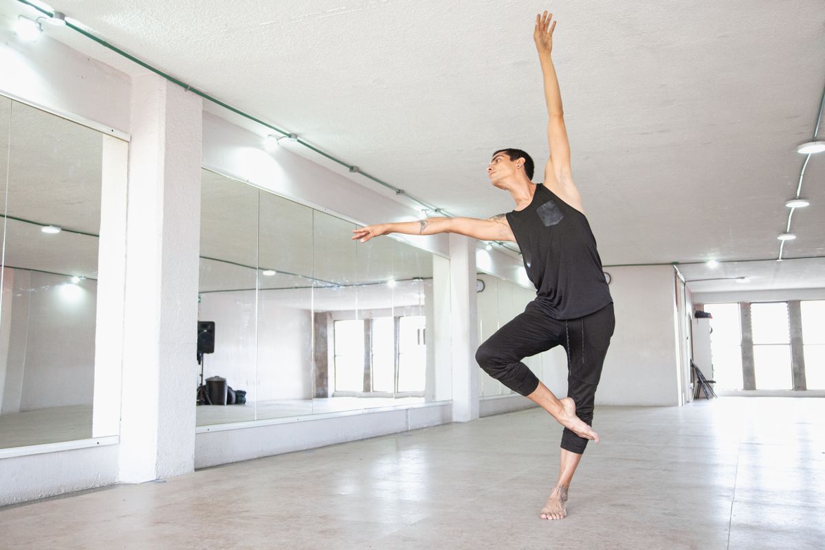 Un danseur classique s'exerce en studio, devant un mur de miroirs