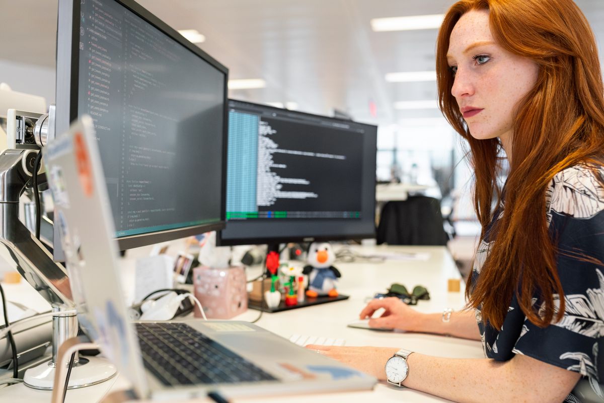 Une développeuse à son bureau, double écran, code visible