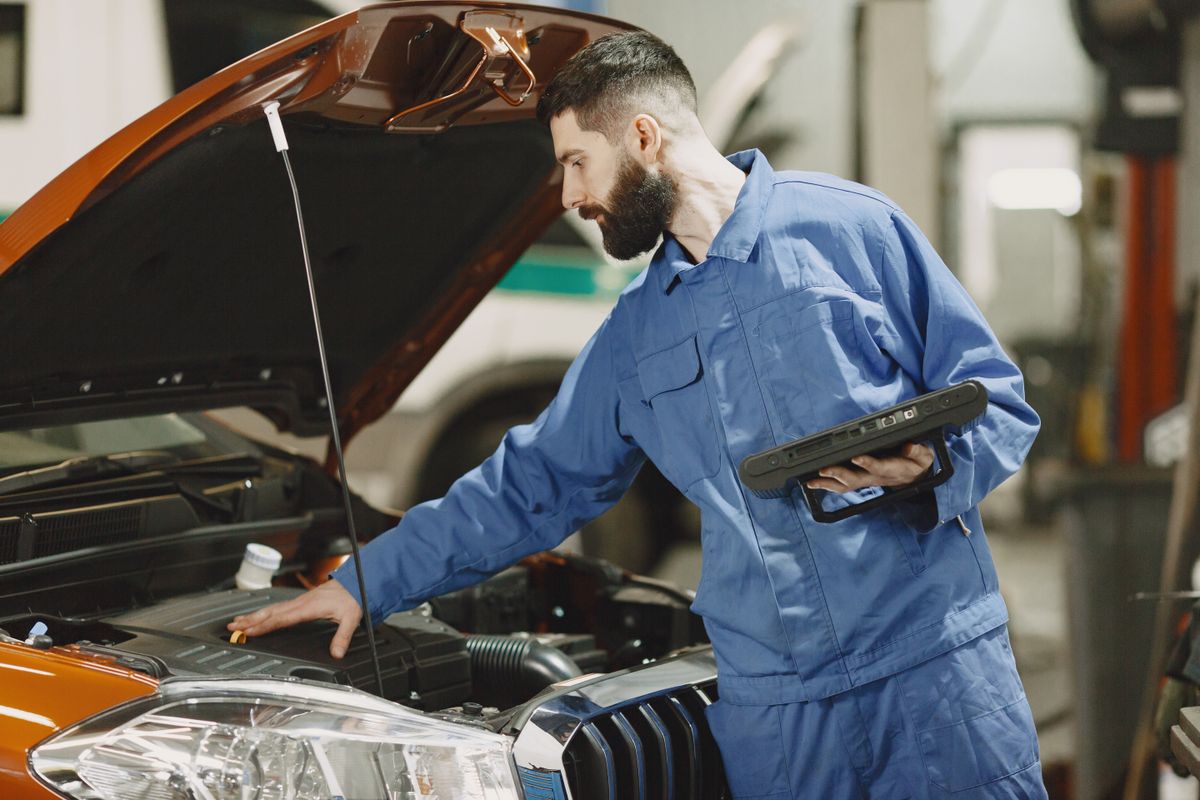 Un mécanicien penché sous le capot d'une voiture, dans un garage