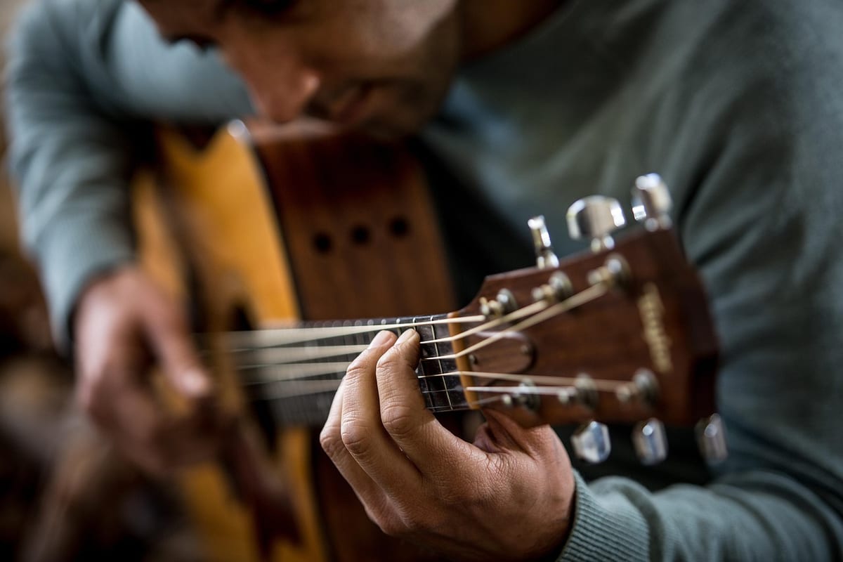 Un guitariste joue, doigts sur le manche