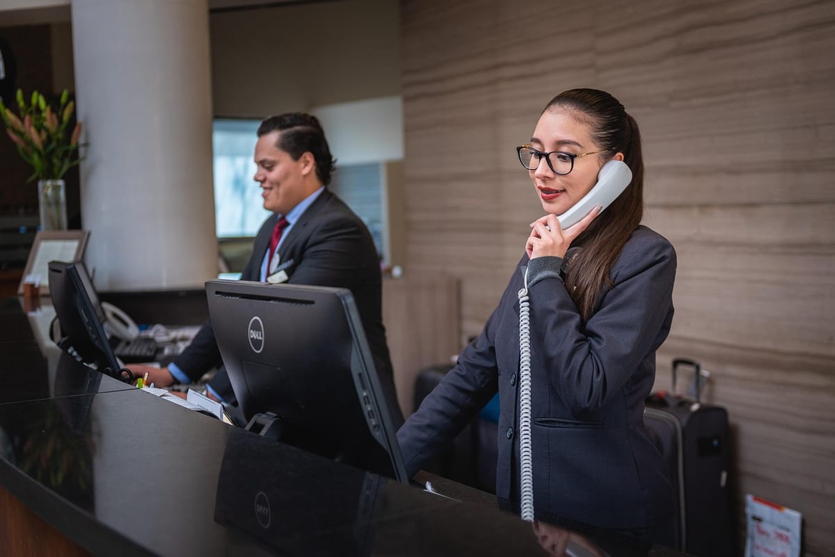 Une réceptionniste répond au téléphone au comptoir d'un hôtel